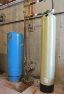 The tall fiberglass tank to the right of the blue pressure tank is filled with calcium carbonate to neutralize acidic well water.