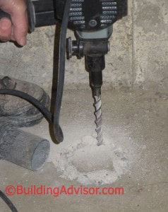 Drilling concrete to install radon mitigation system.