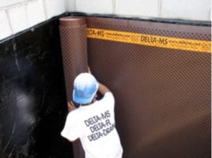 A dimpled membrane is installed on a foundation over spray-on waterproofing to provide an effective waterproofing system.