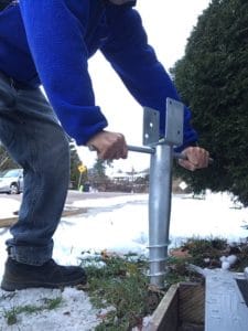 installing a ground screw for a railing post.